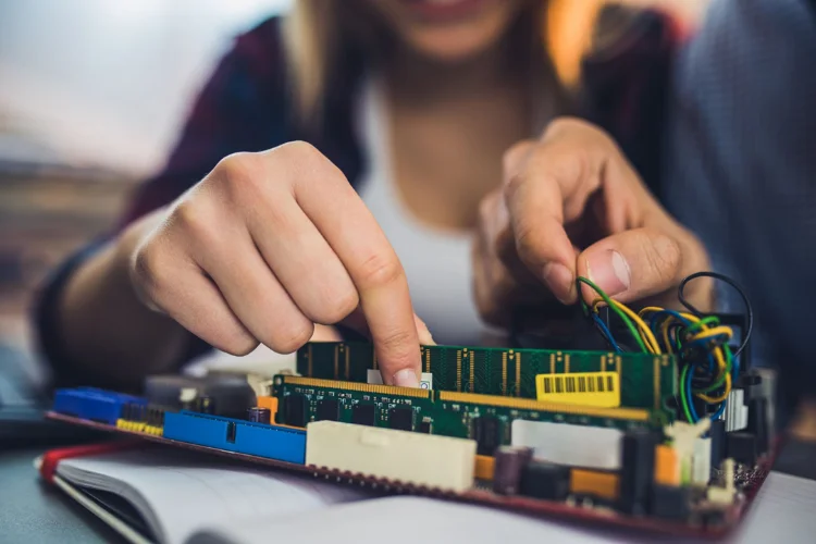 Close-up of hands installing a component into a circuit board